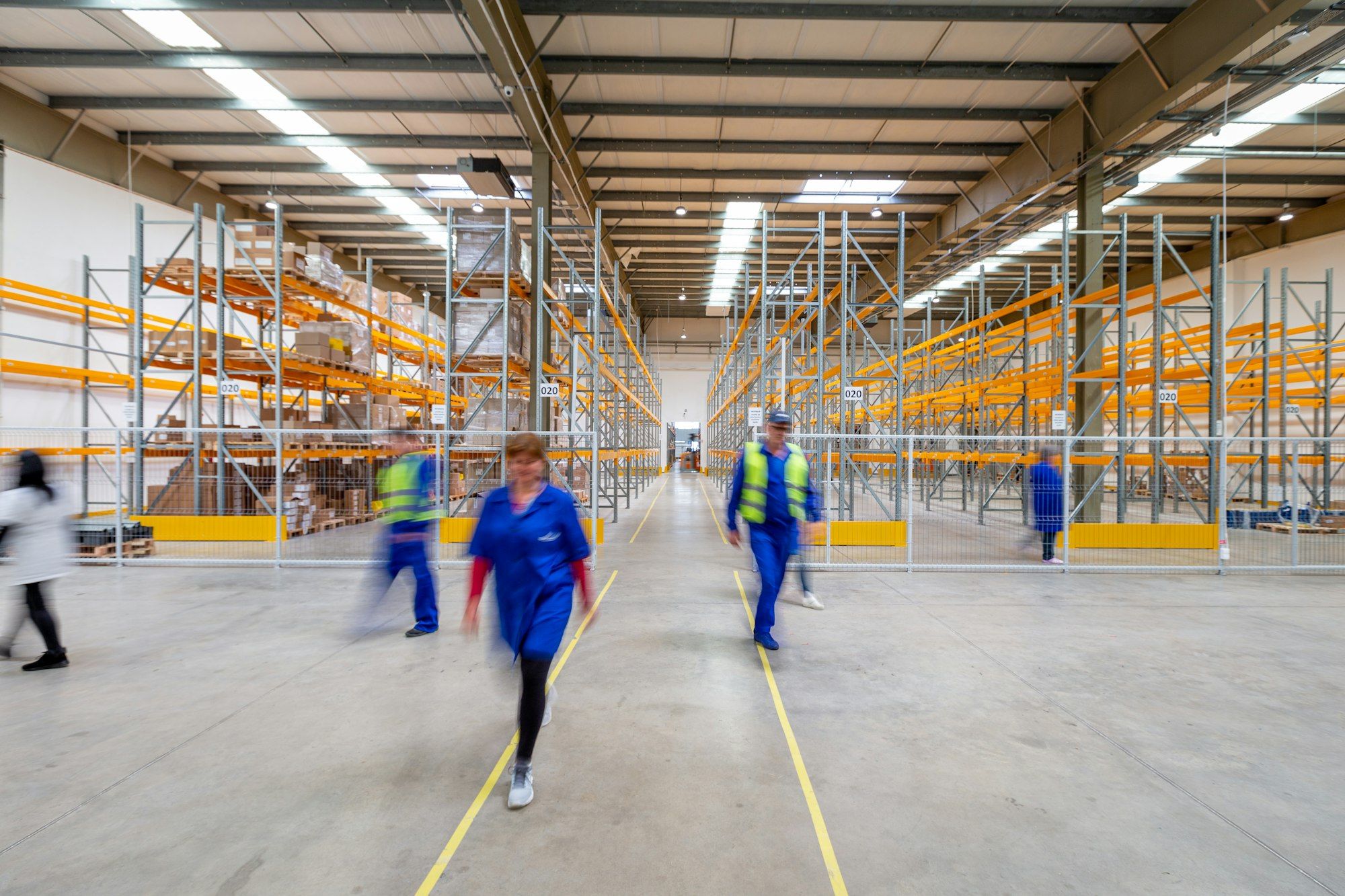 Large logistics warehouse with racking and staff working in the aisles