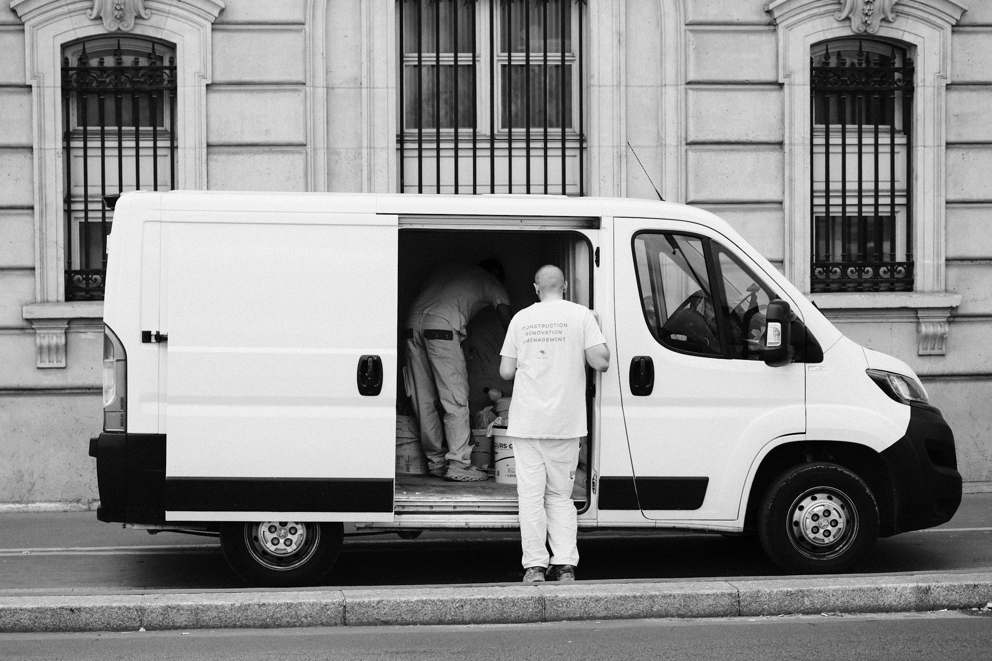 Operarios cargando material en una furgoneta blanca frente a un edificio de oficinas